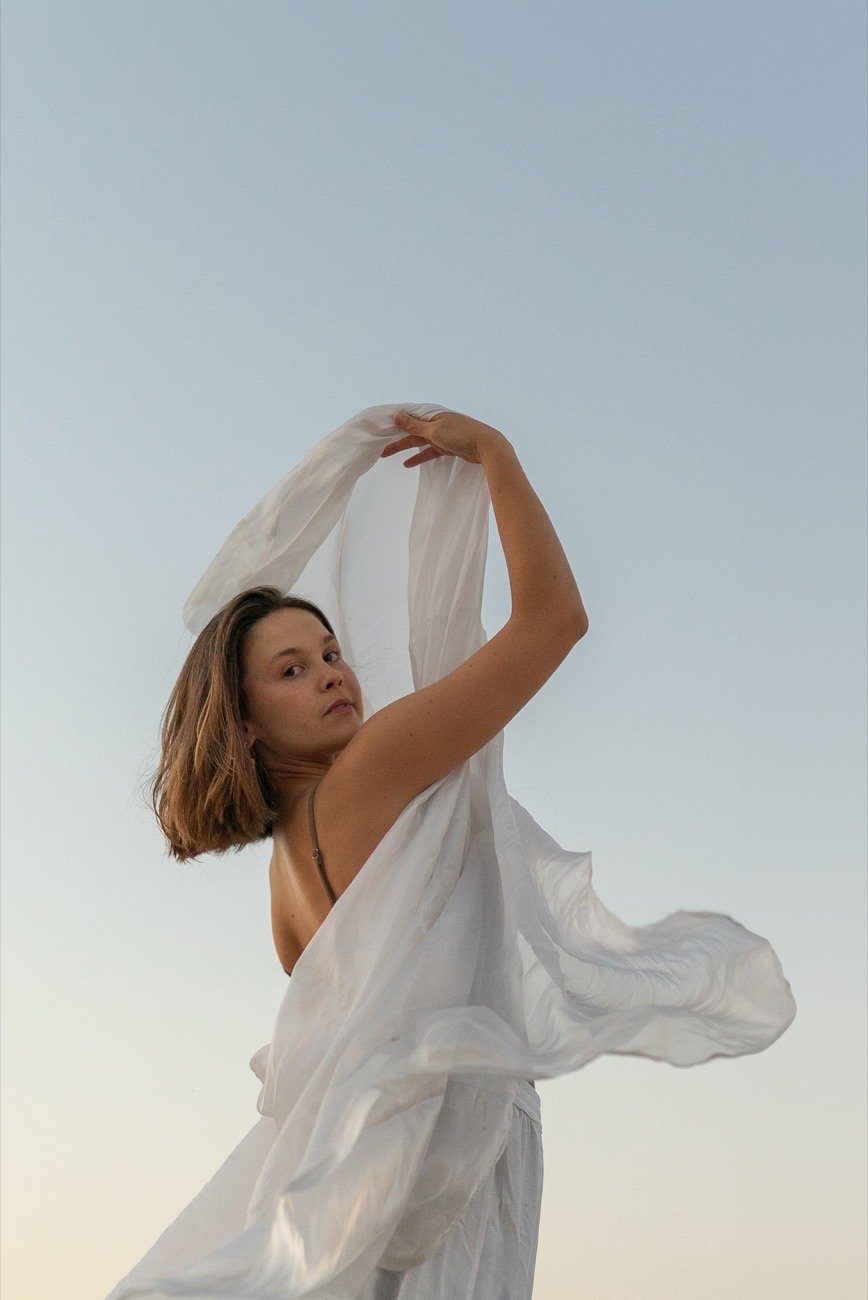 Turning inside a length of white cloth against the sky